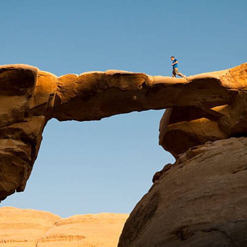 A man jogging across a natural bridge in Wadi Rum, Jordan